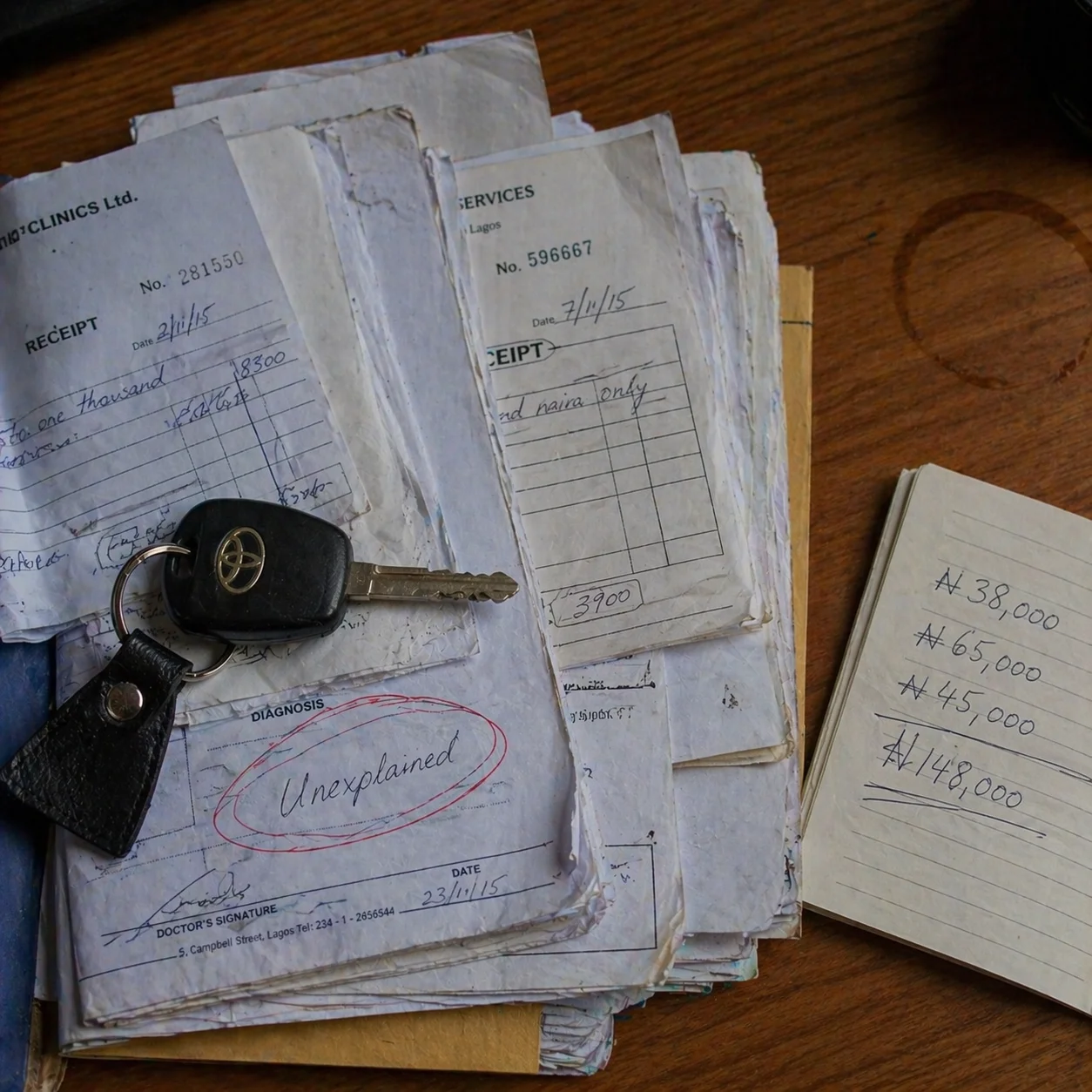 Stack of hospital receipts weighed down by a Toyota key