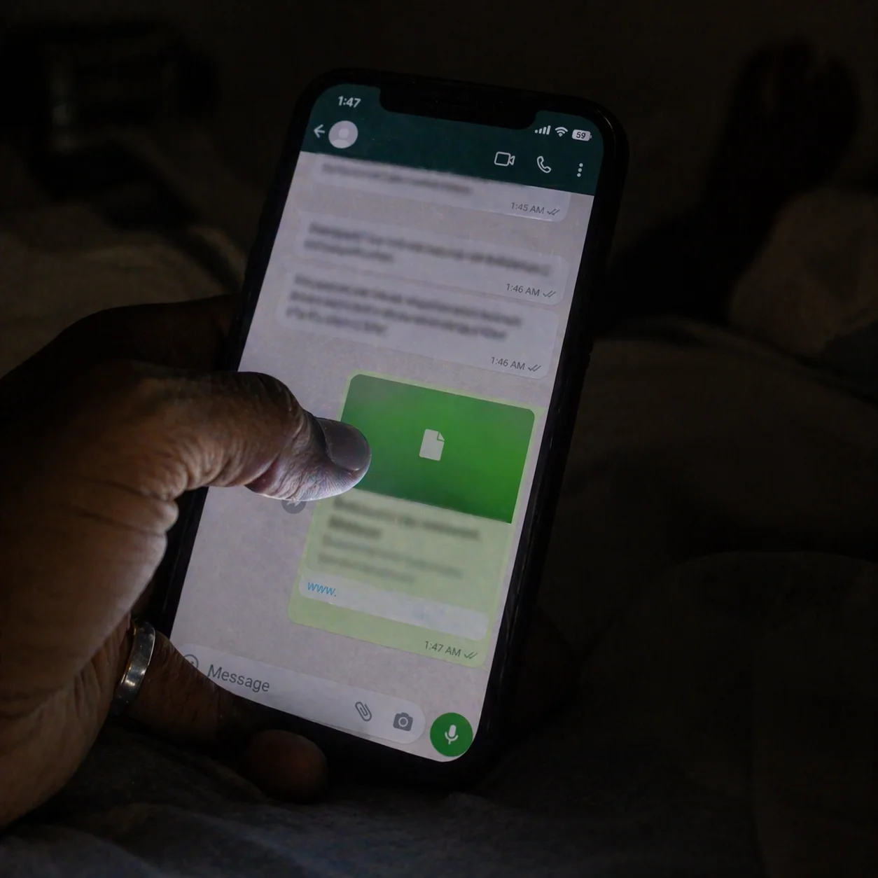 A man's thumb hovering over a WhatsApp link at night