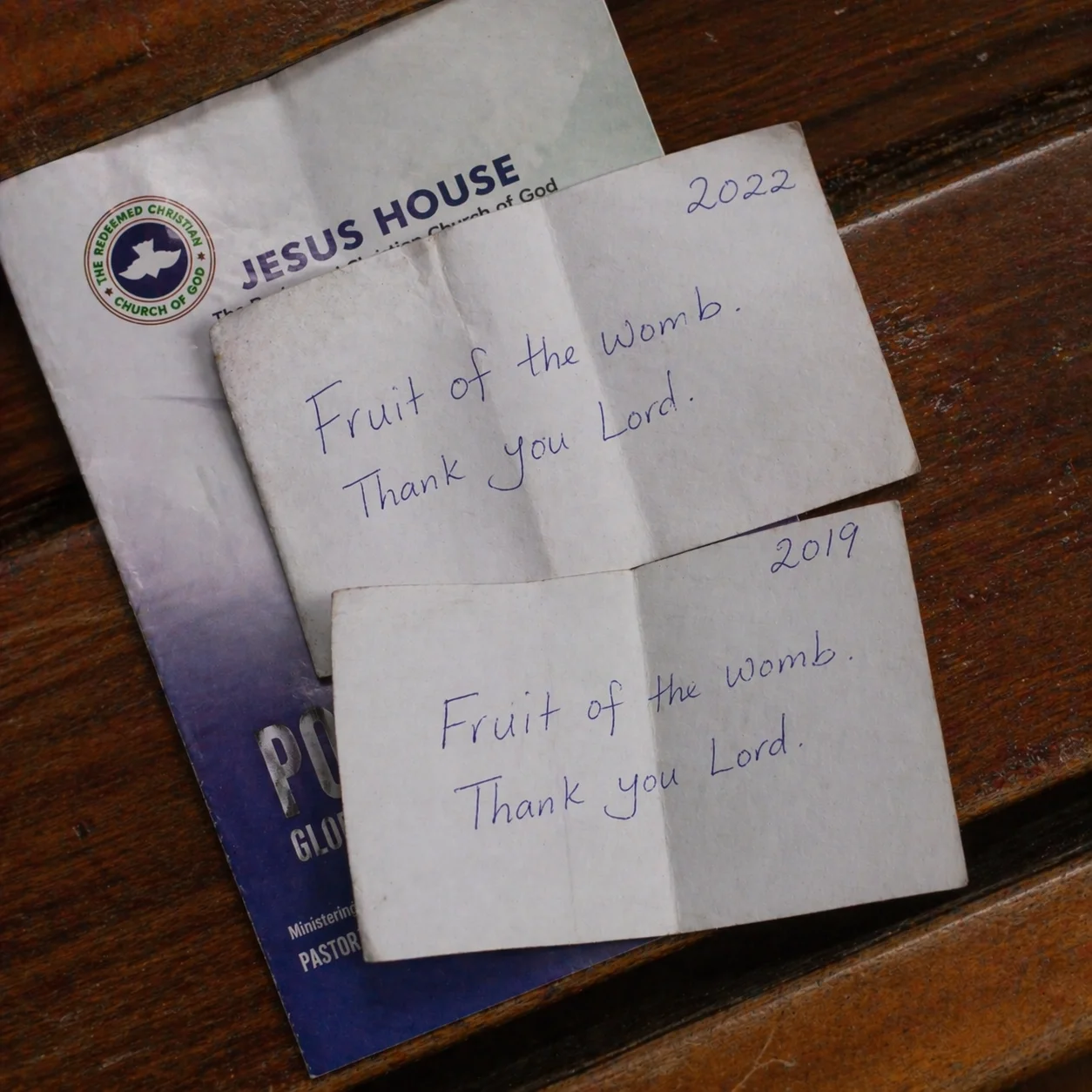 Two prayer request slips on a church pew, same handwriting, years apart, same request
