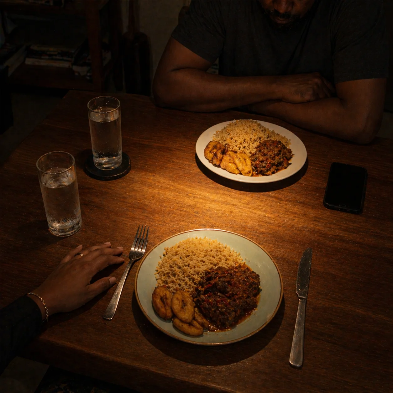 Dinner table set for two, both plates untouched, the silence between them